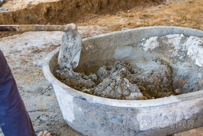 工人在施工现场用锄头在盆式搅拌机中混合水泥