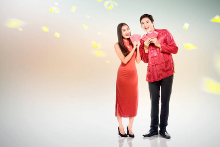 Asian Chinese couple in cheongsam dress holding red envelopes 