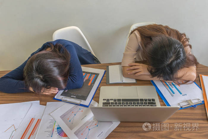 两个办公室女孩睡在办公桌上