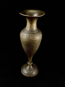 黑色背景的古铜花瓶。有图案和装饰品的铜制盘子。家庭装饰用金属壶。