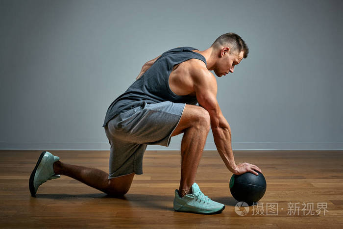 用健身球锻炼身体的强壮男子灰色背景下完美身材的男人照片力量和动力