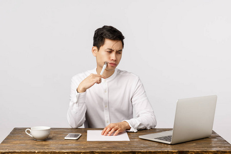 办公用笔工作中严肃忙碌的亚洲年轻人,坐在办公桌上