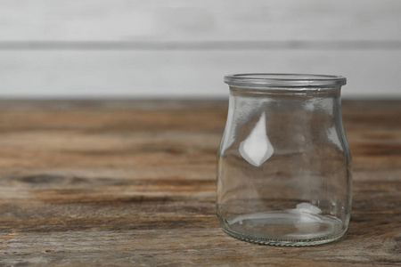 Empty glass jar on wooden table, space for text