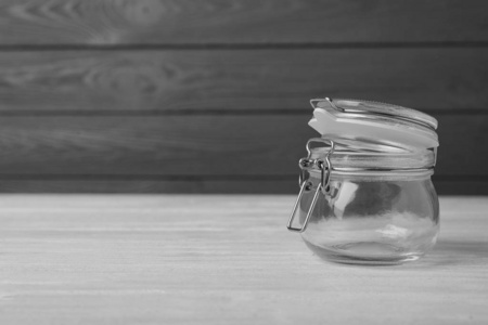 Empty glass jar on white wooden table, space for text