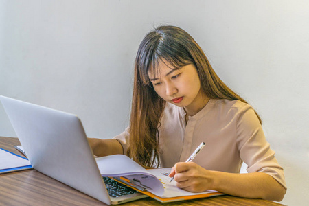 Asian young  lady working on laptop and documents 