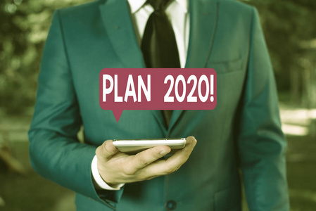 显示2020年计划的文字标志。概念图详细的提案做了一些明年实现某事商人在蓝色套房站着，手里拿着手机。