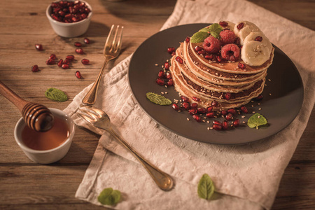 Pancakes with raspberries, banana slices, pomegranate seeds and 