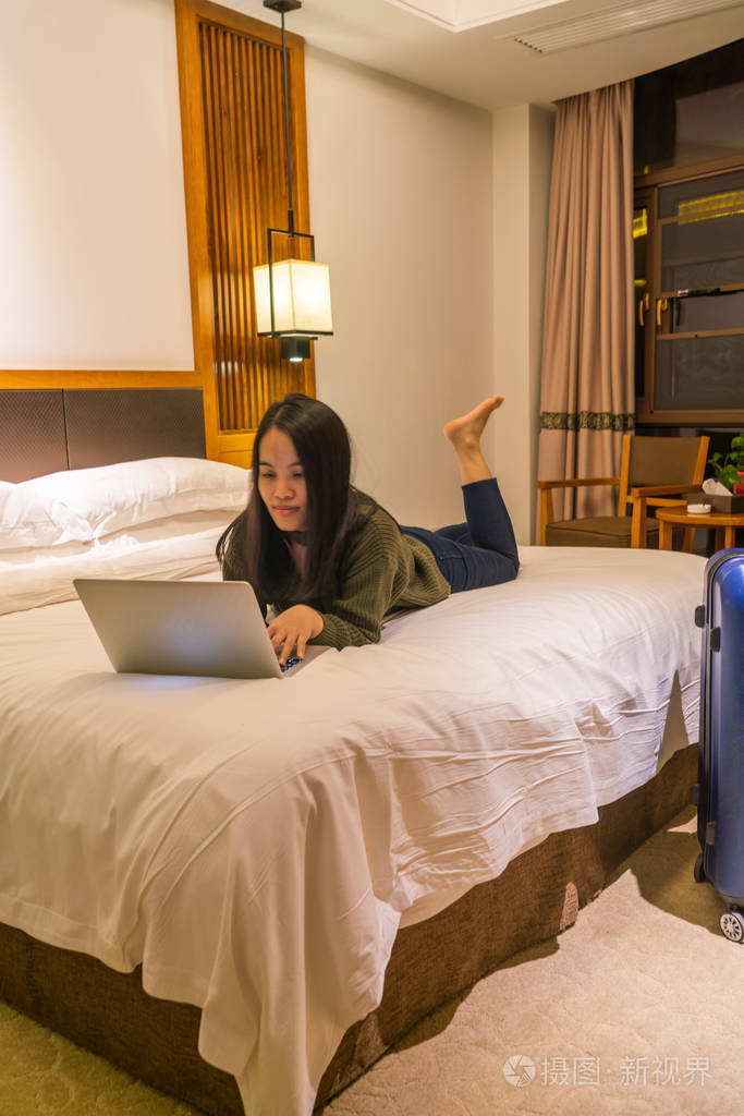 亚洲女人躺在床上用笔记本电脑照片-正版商用图片26poqm-摄图新视界