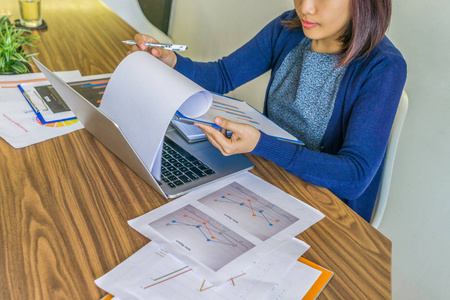 Asian  lady working on laptop and financial chart document