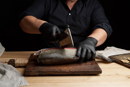 chef in black shirt and black latex gloves slices a whole fresh 