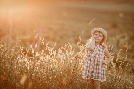 年轻的金发女孩在田野里玩阳光夕阳，穿着一件以希尔为背景的连衣裙