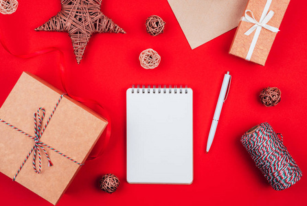 空白笔记本，钢笔，工艺礼品盒，信封，红色蝴蝶结，三色绳芯，缎带和红色节日背景装饰。新年计划。