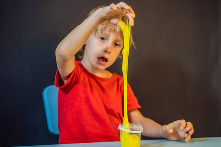 一个男孩玩手工制作的叫做黏液的玩具。小孩玩黏液。小孩挤拉黏液