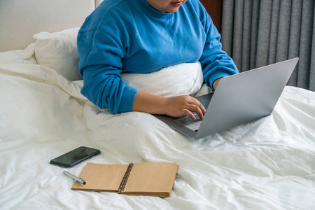 一个女人在白色的床上用手提电脑工作