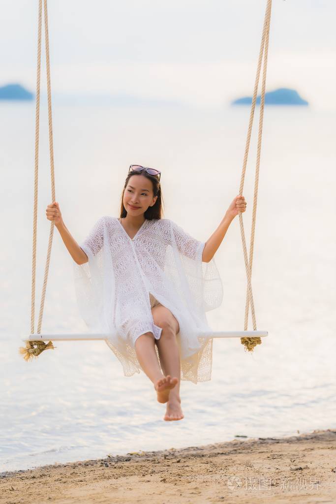 美丽的年轻亚洲女人坐在秋千上