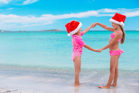 可爱的小女孩戴着圣诞帽在海滩圣诞假期一起玩得开心