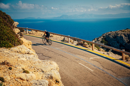 运动员在公路上骑自行车，在美丽的大自然中进行海上运动。