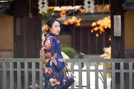 Geishas girl wearing Japanese kimono among red wooden Tori Gate 