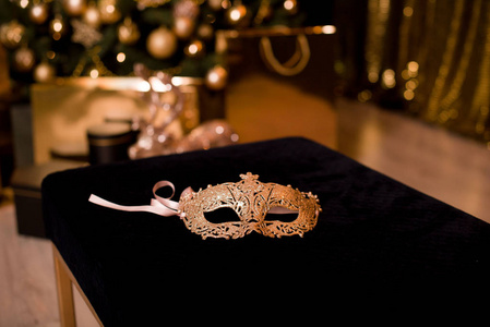 一个美丽的狂欢节面具是蓝色的。背景是一棵金光闪闪的美丽圣诞树。