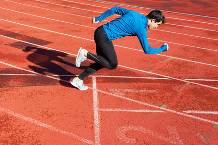 Runner starting his sprint on running track in a stadium. 