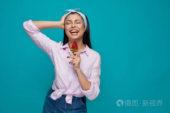 女孩闭着眼睛摆姿势,手里拿着西瓜棒棒糖