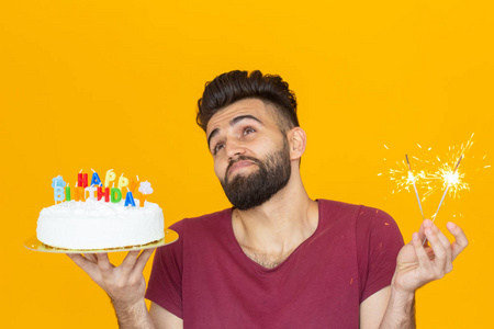 一个有趣的正面人物的画像，手里拿着一个自制的祝贺蛋糕，背景是黄色。概念，乐趣和庆祝。