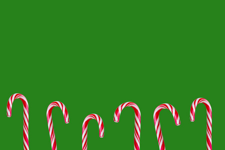 节日的圣诞节红色和白色的糖果棒孤立在绿色的圣诞背景。