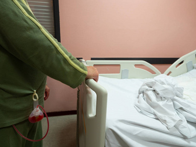 一名男子在手术后拿着引流袋躺在病床上.照片