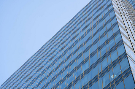 天空在建筑物窗户上的倒影。蓝天上现代玻璃建筑摩天大楼的透视和俯视。商务办公楼或公司大楼的窗户。
