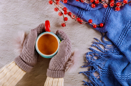 妇女手戴针织羊毛手套，手里拿着一杯热可可。