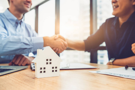 Closeup of real estate broker agent shaking hands with customer 