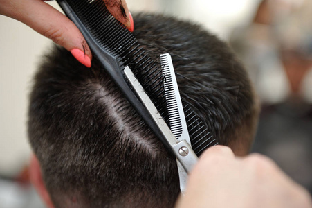 理发师用剪刀和梳子给男人理发