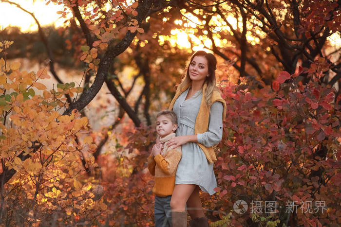 秋天，母子俩穿着暖和的衣服在公园里散步