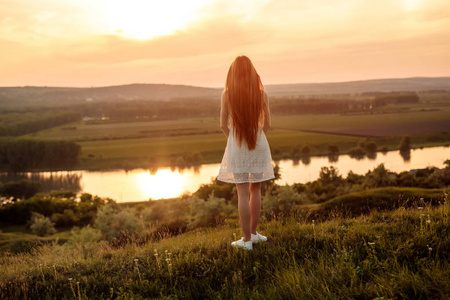 不认识的年轻女子在河边欣赏日落
