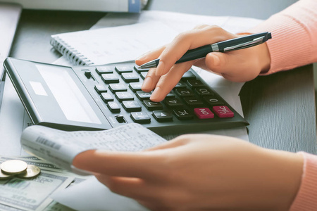 一位女会计手里拿着一张出纳支票,用计算器计算.