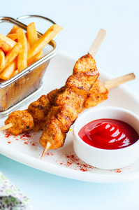 Baked chicken kebabs In a plate with potato fries and ketchup. 