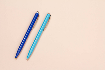 两支米色背景的塑料笔.照片