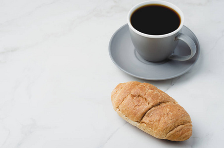 Coffee break. Grey cup with black coffee and croissant on white 