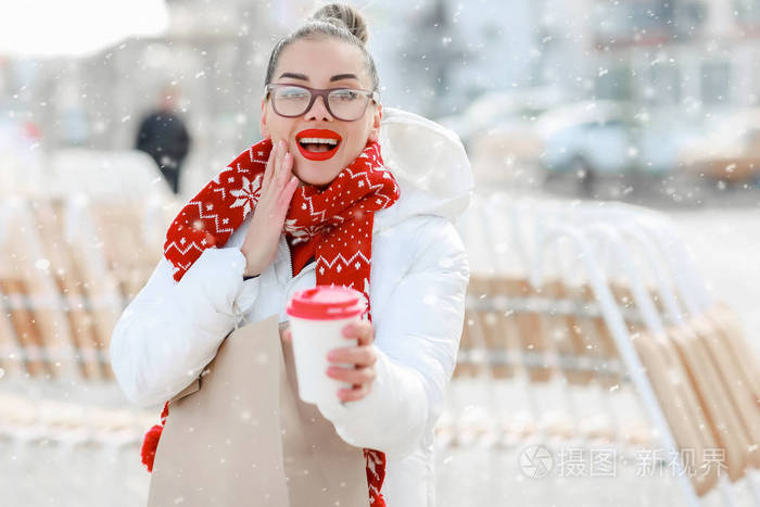 戴着眼镜和红毛衣的女人在街上喝咖啡
