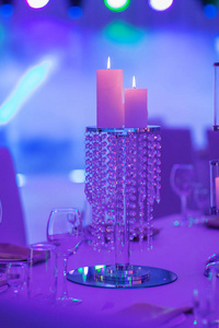 宴会厅内的喜庆餐桌上，用蜡烛和银烛台组成的彩灯装饰。为新婚夫妇在婚宴区用餐。