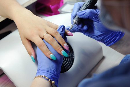 Repair old gel nails with a nail grinder in the nail salon. The 