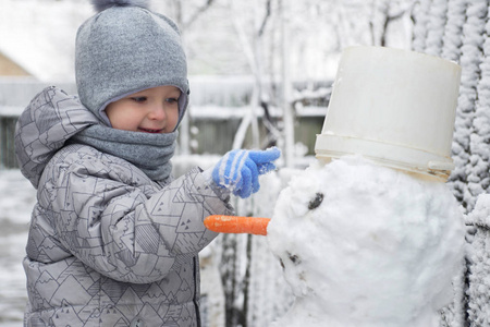 可爱的小男孩正在堆雪人。孩子在玩雪。儿童冬季户外活动时间概念