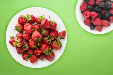 草莓放在白色盘子的俯视图上。背面是草莓