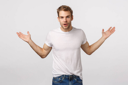 迷茫而粗心的帅气金发白种人横摊双手质问,耸耸肩问问题,听不懂,不