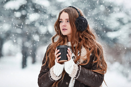 在下雪的冬日里，快乐的年轻女人喝着咖啡。女孩e