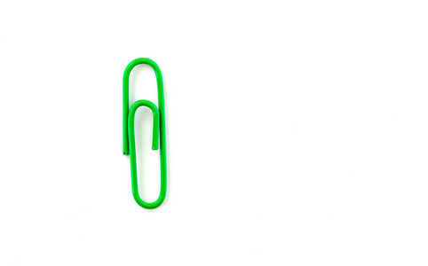 Green paper clip isolated on white background. Close up and top 