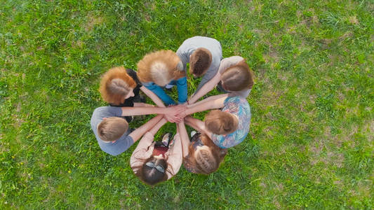 友好的朋友和团队合作的概念.兴高采烈的朋友们手拉手在中心四散.