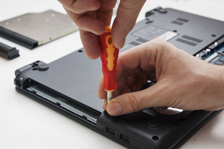 Using a screwdriver, the master dismantles the laptop case 