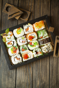 一套深色背景的传统日本食品。寿司卷马赛克图案木制黑框。垂直图像