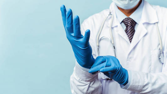 医生戴上橡胶手套，戴上医疗和药品。蓝色背景隔离